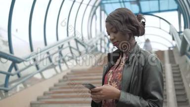 非裔美国女孩，学生在街道、城市街道、地铁里用她的手机工作，快乐地关门